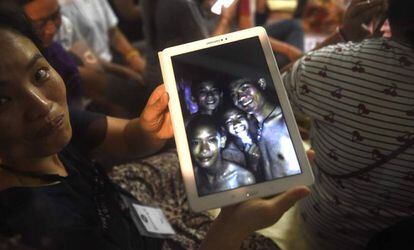 Uma familiar mostra uma foto de alguns dos desaparecidos tirada dentro da gruta pelas equipes de resgate nesta segunda-feira, na Tailândia.