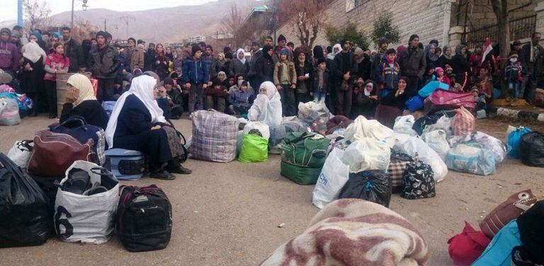 Um grupo de sírios espera a chegada da ajuda humanitária em Madaya.