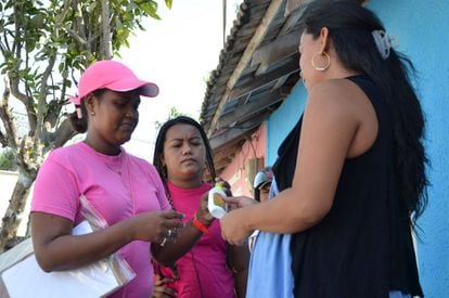 Funcionária distribui repelentes e preservativos a várias mulheres em Barranquilla, na Colômbia, na campanha contra o zika.