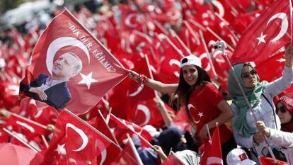 Dois jovens agitam bandeiras da Turquia e com a efígie de Erdogan
