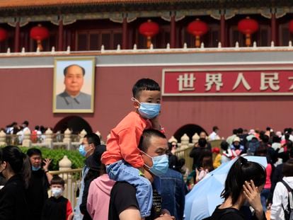 Homem carrega uma criança usando máscaras na visita à Cidade Proibida, em Pequim.