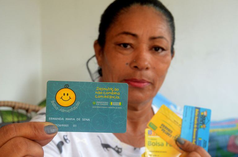Ermanda Maria de Sena, a primeira usuária cadastrada do Bolsa Família, mostra o cartão do Bolsa-Alimentação com o número 01