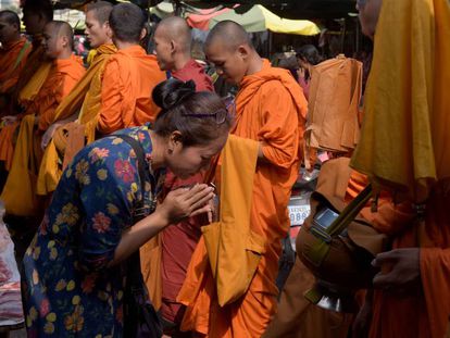 Uma mulher diante de monges budistas no Camboja.