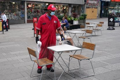 Funcionário limpa mesa em uma calçada quase vazia em Times Square, no final de junho.