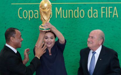 A presidenta Dilma Rousseff eleva o troféu ao lado do ex-jogador Cafu e de Joseph Blatter nesta segunda-feira.