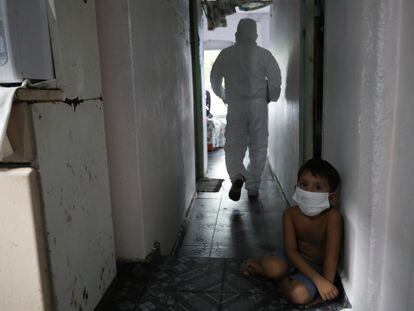 Criança olha para um trabalhador municipal de saúde em Manaus, que sofre novo colapso no sistema de saúde durante a pandemia.