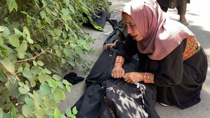 Mulher chora diante de um hospital de Cabul ao lado do corpo de uma vítima do atentado.