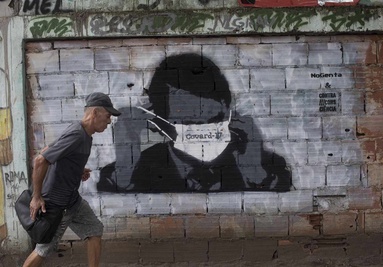 Um homem passa por um grafitti de Jair Bolsonaro durante a pandemia de coronavírus, no Rio de Janeiro, nesta terça-feira.