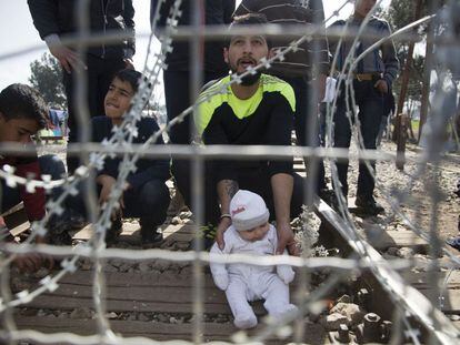 Homem e seu filho na fronteira entre a Grécia e a Macedônia, nesta terça-feira.