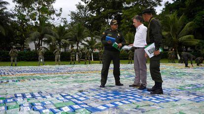 O presidente da Colômbia, Juan Manuel Santos, e dois agentes sobre as mais de 12 toneladas de cocaína apreendida