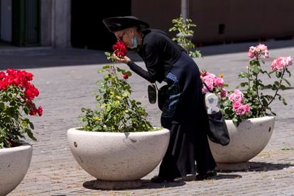 Uma mulher baixa a máscara para cheirar rosas em Roma, em maio passado, em pleno confinamento.
