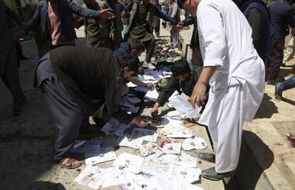 Afegãos recolhem documentos e fotos das pessoas mortas e feridas no atentado deste domingo em Cabul.