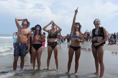 Jovens observam da praia o lançamento do 'Dragon Crew', na Flórida.