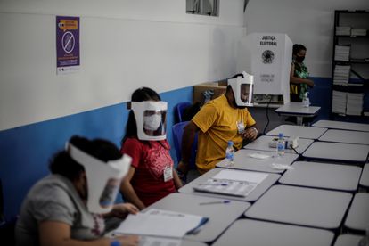Mesários voluntários trabalham em zona eleitoral no Rio de Janeiro durante o primeiro das eleições. 