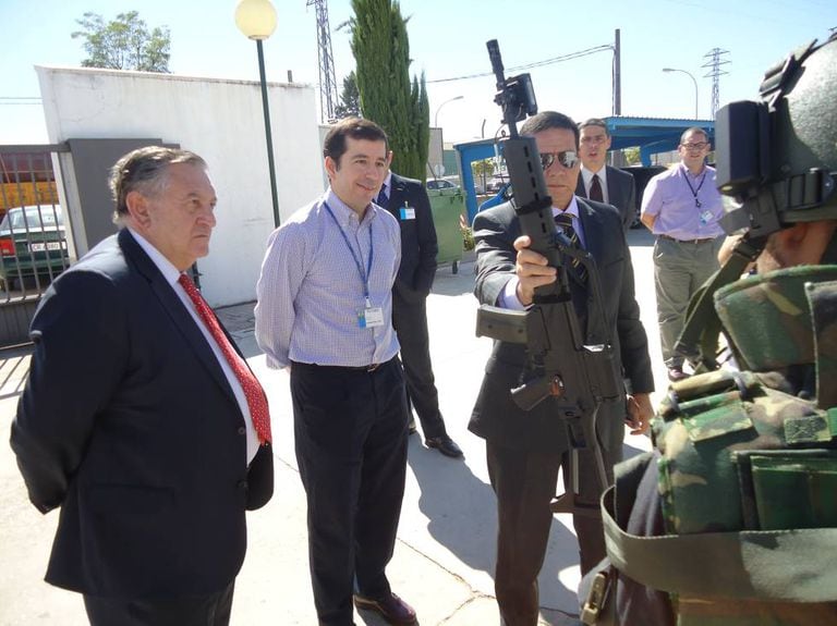 Tom Sarobe, de gravata vermelha à esquerda, junto com o general Mourão, que segura uma arma.