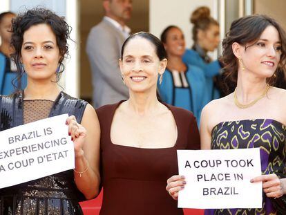 Maeve Jinkings, Sonia Braga e Emilie Lesclaux, do filme Aquarius, mostram cartazes em Cannes que dizem 'Brasil vive um golpe de Estado'.