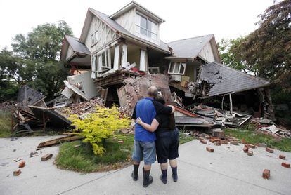 Um casal, diante de sua casa destruída em Christchurch.