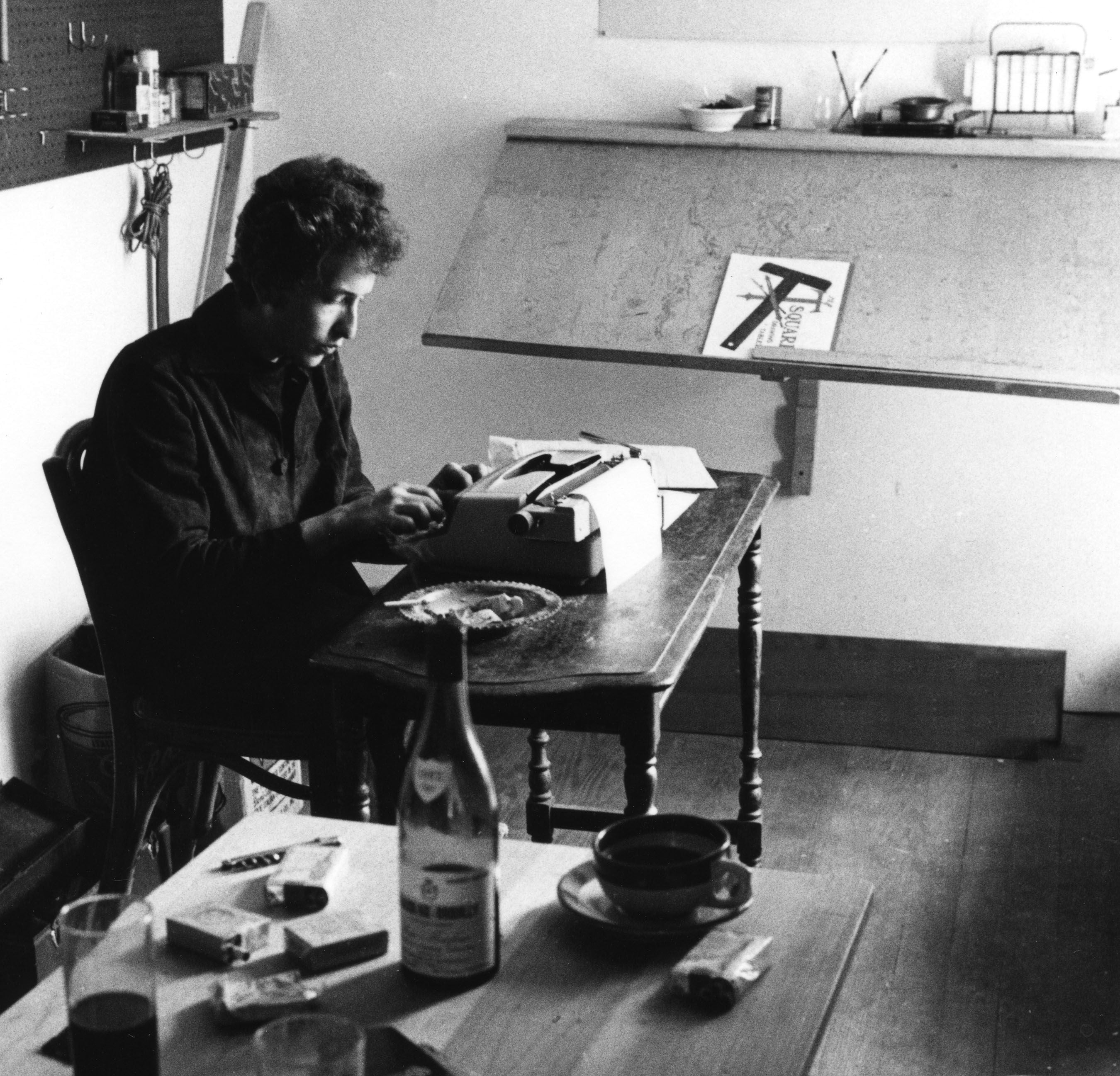 Bob Dylan usando uma máquina de escrever em seu escritório de Woodstock, Nova York, no verão de 1964, em uma imagem de Douglas R. Gilbert. 