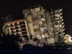 The rest of the Champlain South tower is seen being demolished in Surfside, Florida, north of Miami Beach, late on July 4, 2021. - A controlled explosion brought down the unstable remains of the collapsed apartment block in Florida late on July 4 ahead of a threatening tropical storm as rescuers prepare to resume searching for victims. (Photo by Giorgio VIERA / AFP)