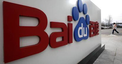 Uma mulher caminha junto ao logótipo de Baidu em sua sede de Beijing.