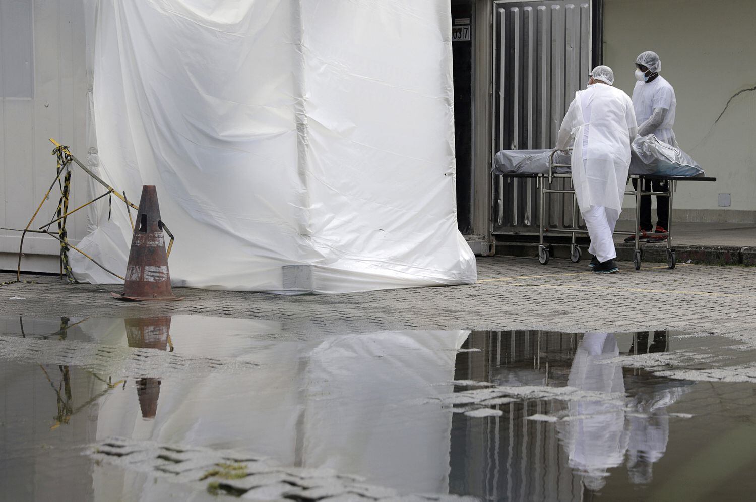 Profissionais de saúde vestindo equipamentos de proteção transportam o corpo de uma pessoa no Rio de Janeiro, em maio.