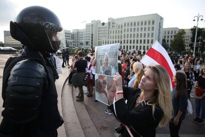 Uma mulher segura uma foto em frente a um policial de uma pessoa torturada durante protesto em Minsk neste sábado.