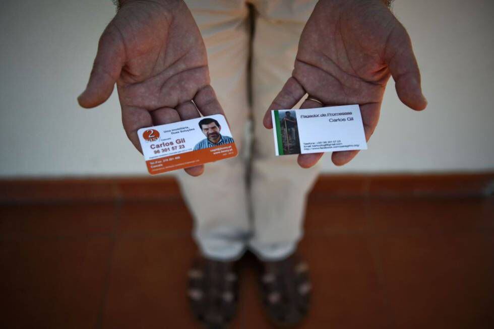 Carlos Gil mostra seus cartões de trabalho: agente imobiliário (à esquerda) e pagador de promessas.