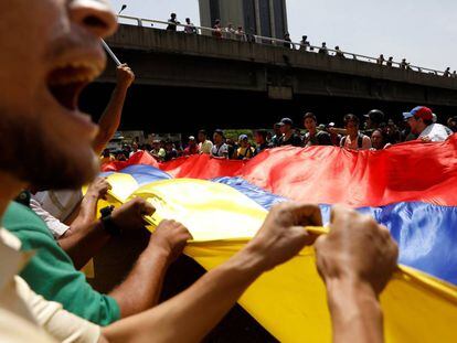 Manifestantes contrários a Maduro erguem bandeira da Venezuela.