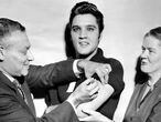 UNITED STATES - OCTOBER 28:  Elvis Presley receiving a polio vaccination from Dr. Leona Baumgartner and Dr. Harold Fuerst at CBS studio 50 in New York City.  (Photo by Seymour Wally/NY Daily News Archive via Getty Images)