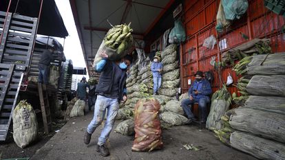 Um homem de máscara carrega um saco de milho em Corabastos, um dos maiores centros de distribuição de alimentos da América Latina, em Bogotá (Colômbia), na terça-feira da semana passada.