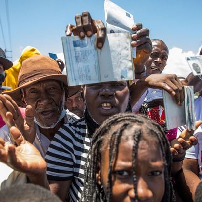 Haitian citizens hold up their passports as they gather in front of the US Embassy in Tabarre, Haiti on July 10, 2021, asking for asylum after the assassination of President Jovenel Moise explaining that there is too much insecurity in the country and that they fear for their lives. - The widow of slain Haitian leader Jovenel Moise, who was critically wounded in the attack that claimed his life, issued her first public remarks since the assault, calling on the nation not to "lose its way." According to Haitian authorities, an armed commando of 28 men -- 26 Colombians and two Haitian-Americans -- burst in and opened fire on the couple in their home. So far, 17 have been arrested, and at least three were killed. A handful remain at large, police say. No motive has been made public. (Photo by Valerie Baeriswyl / AFP)