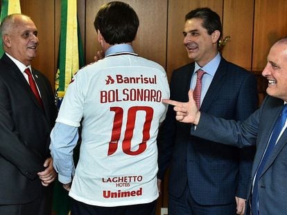 Presidente do Inter (à esq.) presenteia Bolsonaro com uma camisa colorada, em março de 2019.