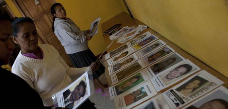Várias mulheres colocam retratos de migrantes desaparecidos durante a nona caravana.