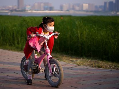 Uma menina anda de bicicleta num parque de Wuhan.