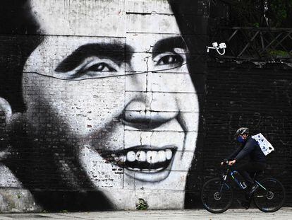 Homem com máscara passa de bicicleta em frente a mural com imagem de Carlos Gardel, em Buenos Aires, em 4 de maio de 2020.