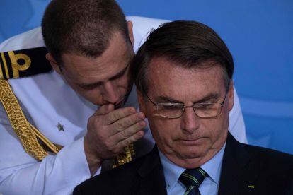Um militar fala ao ouvido de Bolsonaro.