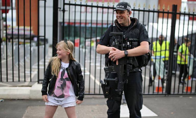 Menina posa com um policial antes do show de Ariana Grande em Manchester, neste domingo.