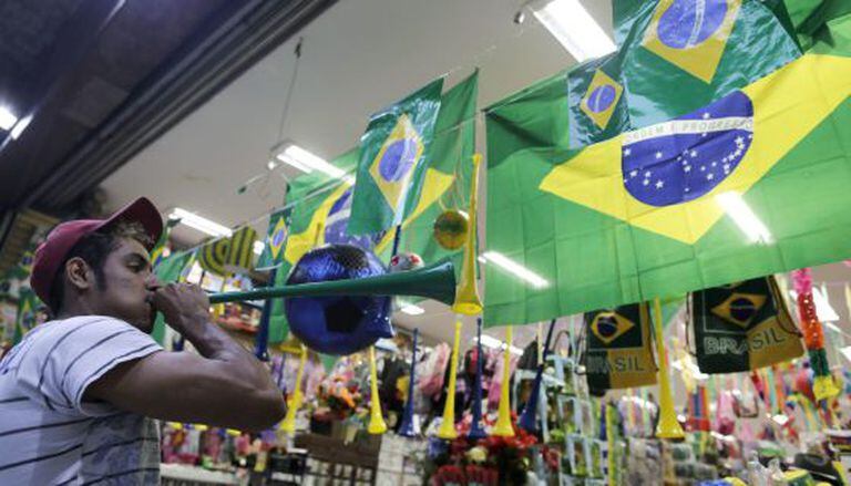 Um homem toca vuvuzela em frente a uma loja de São Paulo. O instrumento está proibido nos estádios.