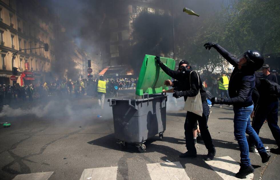 Um manifestante com capacete lança uma garrafa de vidro, durante os distúrbios deste sábado em Paris.