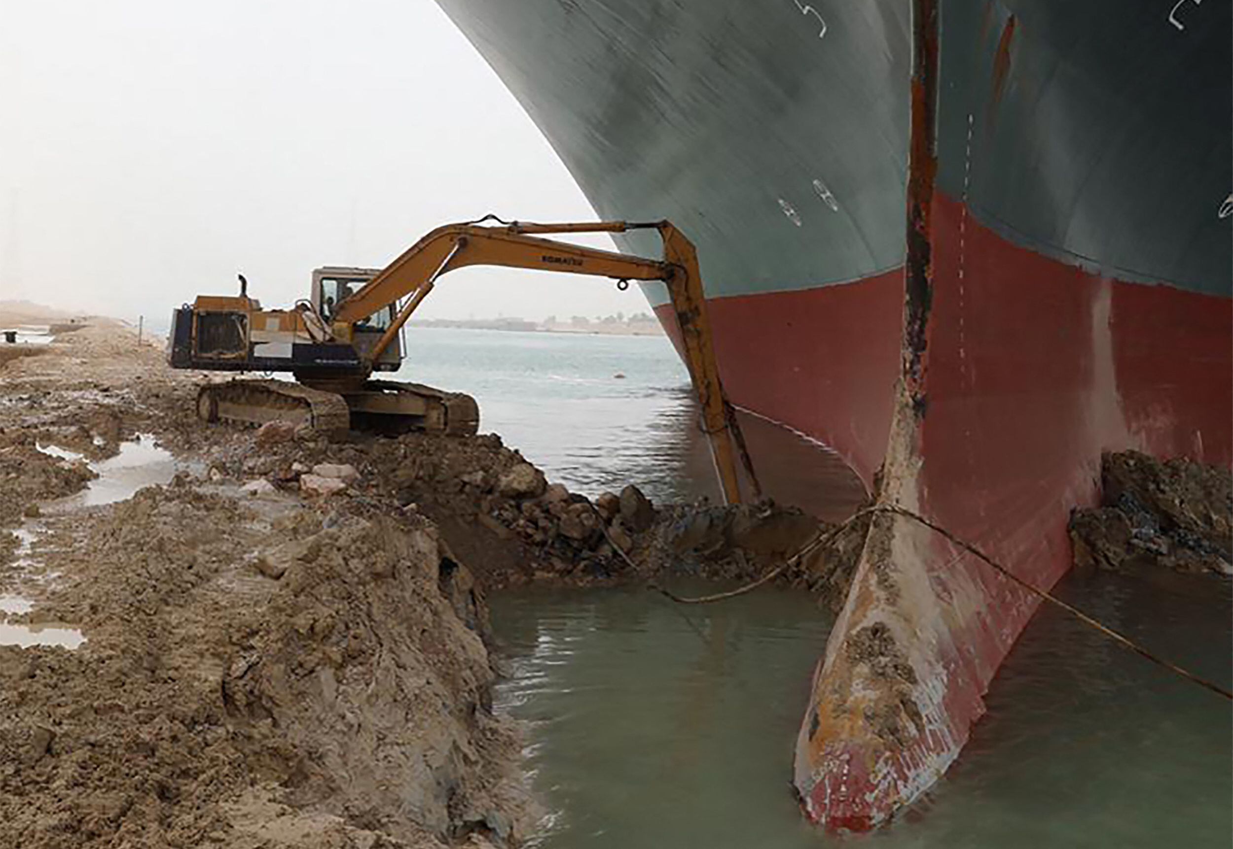 Escavadora retira terra ao redor do navio Ever Given, encalhado no canal de Suez. 