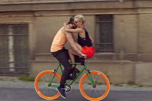 Casal anda em bicicleta colorida pelas ruas de Berlim.