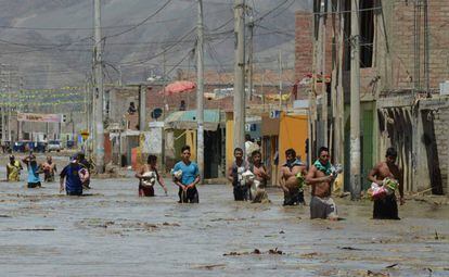 No norte de Lima, moradores caminham na água barrenta.