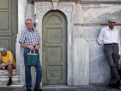 Três aposentados esperam em frente à sede do Banco Nacional da Grécia no dia 9 de julho.