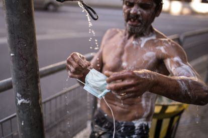 Morador de rua lava máscara em torneira improvisada em São Paulo, na última terça-feira. ANDRÉ LUCAS /