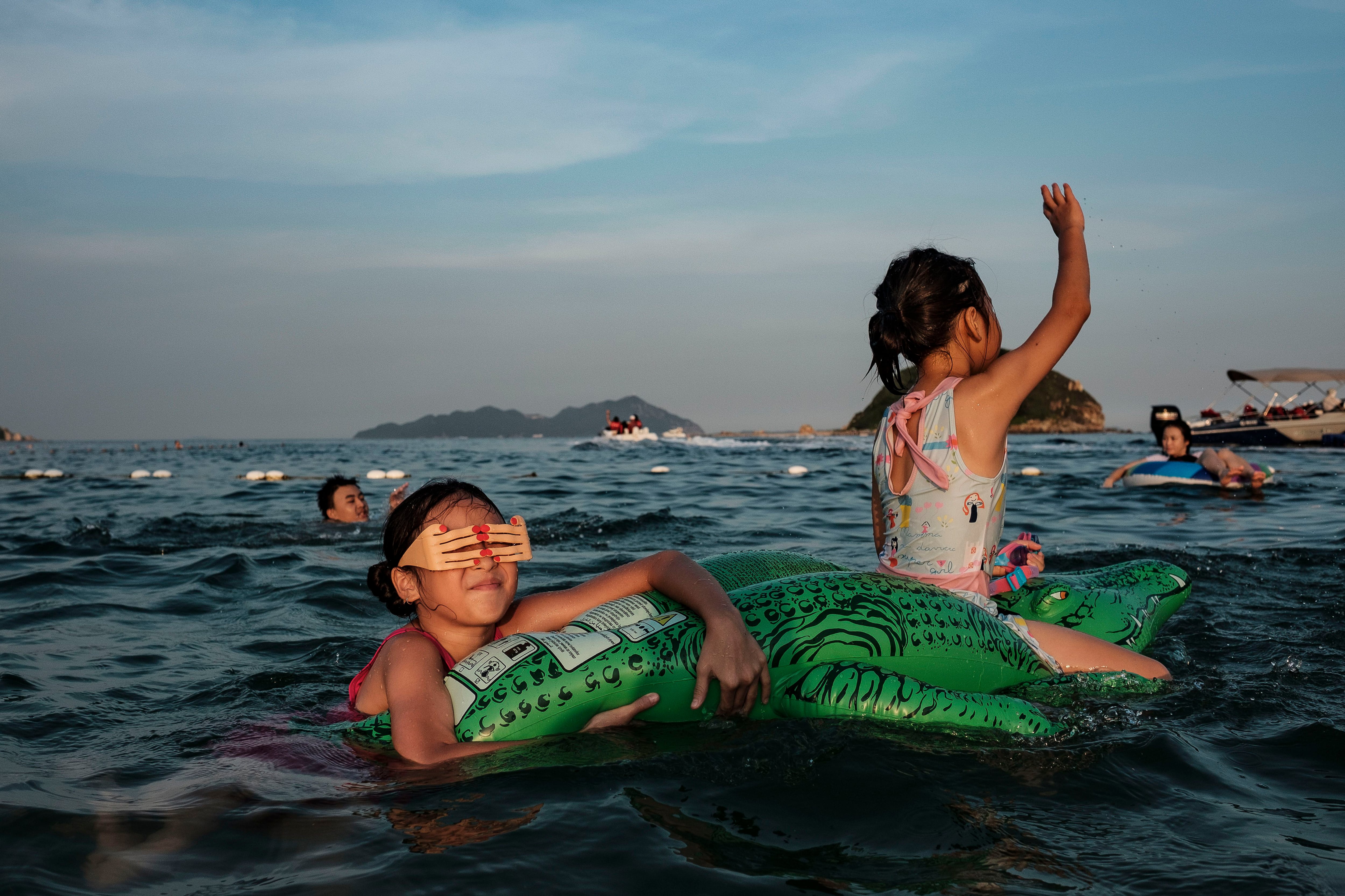 Duas meninas utilizam uma boia para flutuar na praia de Xichong. 