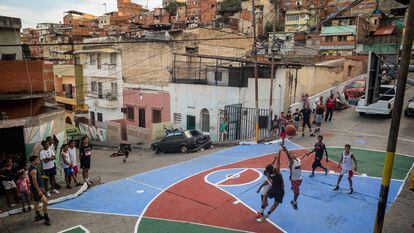 Crianças e jovens jogam basquete em uma quadra restaurada pelos moradores em um bairro de Caracas.
