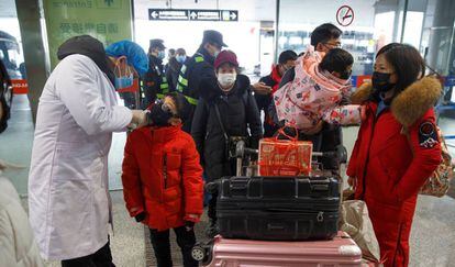 Médico mede a temperatura de passageiros antes do embarque no aeroporto de Changsha, na China.