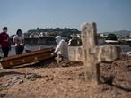 Rodrigo Bessa, left, attends the burial of his mother Edenir Rezende Bessa, who is suspected to have died of COVID-19, in Rio de Janeiro, Brazil, Wednesday, April 22, 2020. After visiting 3 primary care health units she was accepted in a hospital that treats new coronavirus cases, where she died on Tuesday. (AP Photo/Leo Correa)