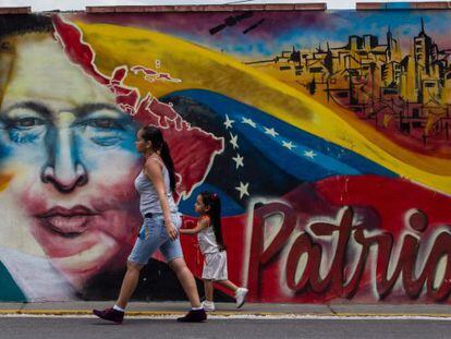 Mulher caminha em frente a um mural de Chávez.