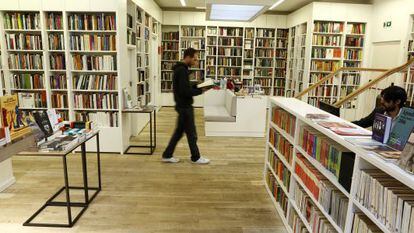 Homem caminha enquanto lê um livro na livraria Juan Rulfo, em Madri.